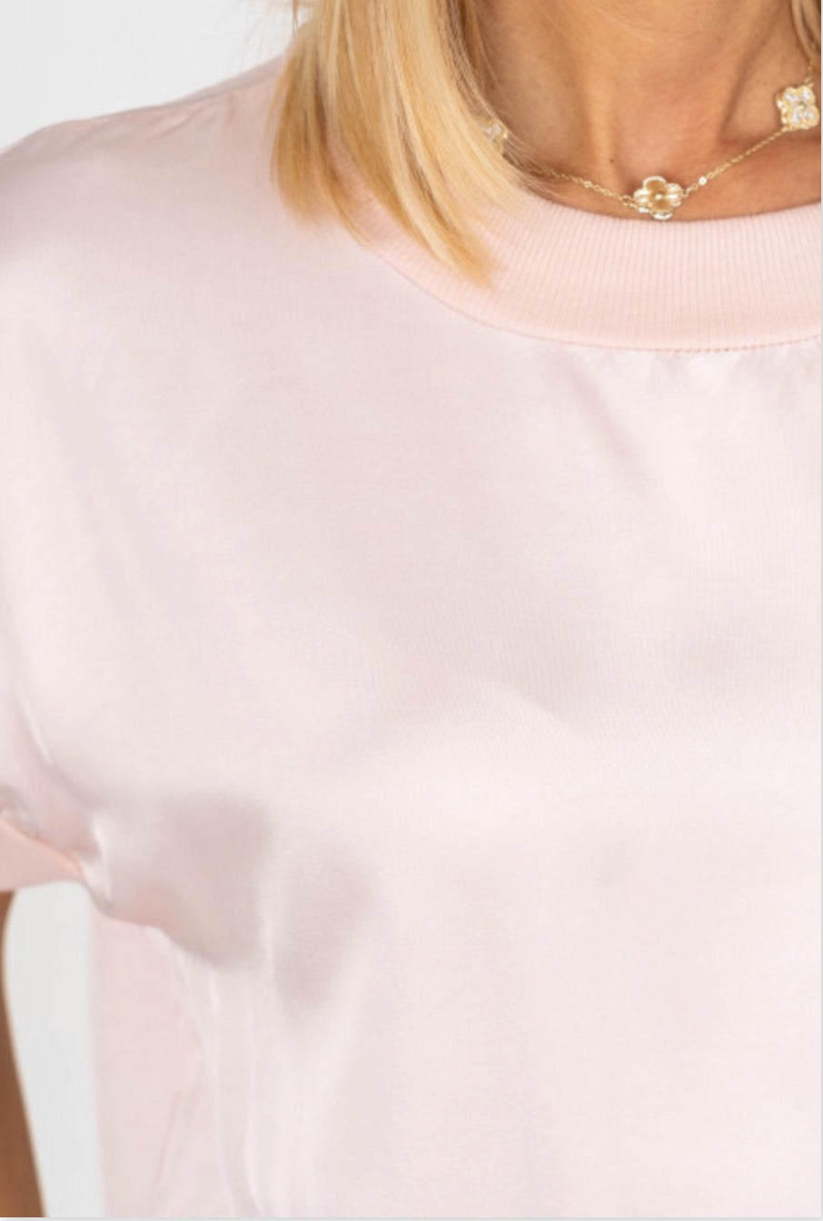 Close-up of a person wearing a light pink top with a blurred background