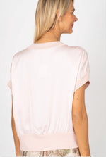 Woman wearing a light pink blouse against a white background