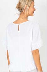 Woman wearing a white blouse with a cut-out back design on a plain background