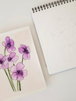Notebook with a drawing of purple flowers on a light surface