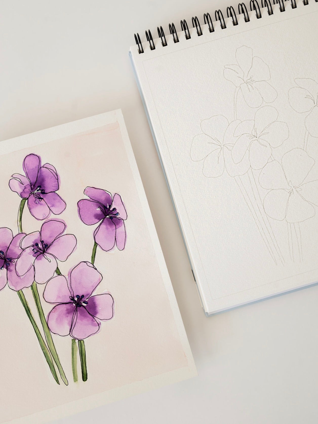 Notebook with a drawing of purple flowers on a light surface