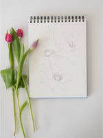 Notebook with floral sketches and pink tulips on a light gray background