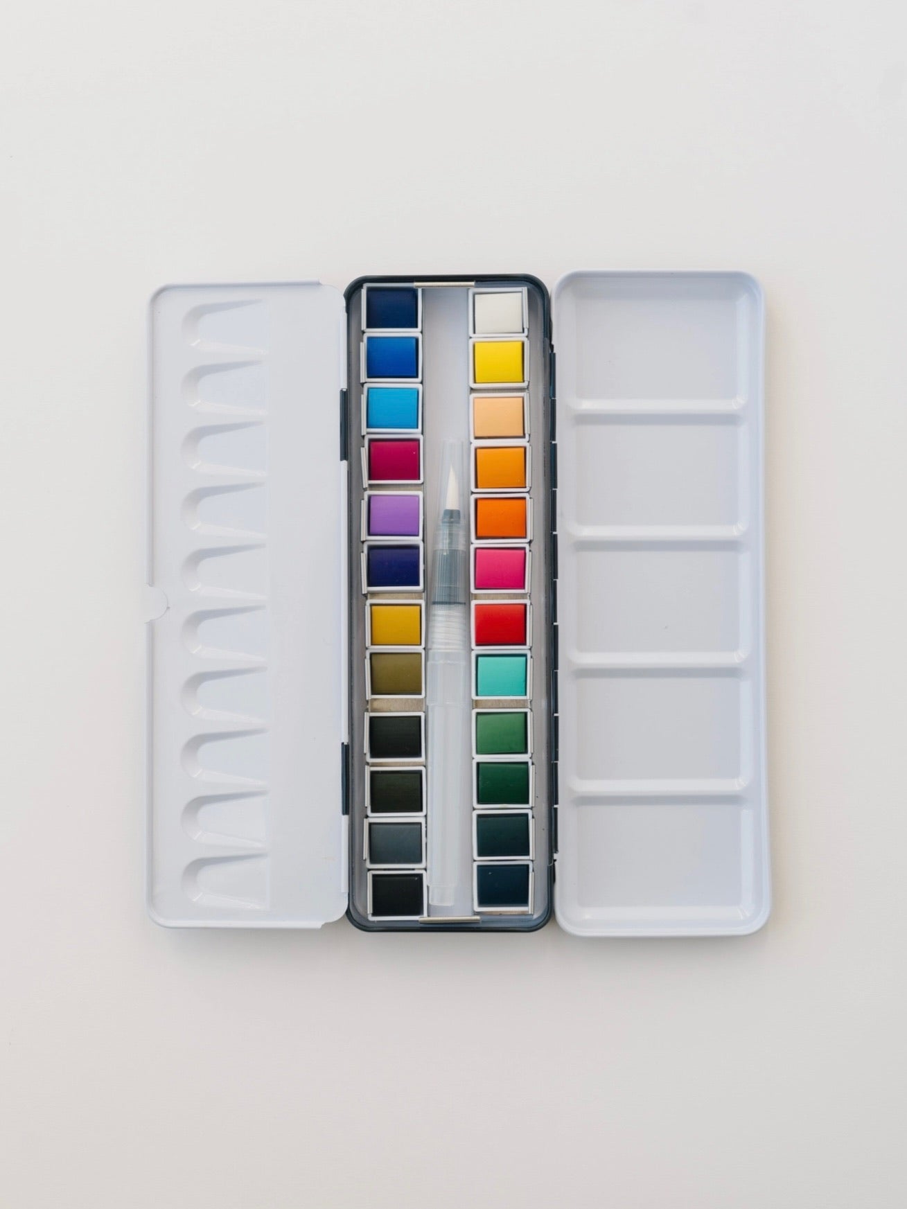 Open watercolor palette with various colors on a light gray background