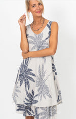 Taupe and navy palm print dress with a sleeveless design and soft, flowing silhouette, shown on a mannequin indoors.
