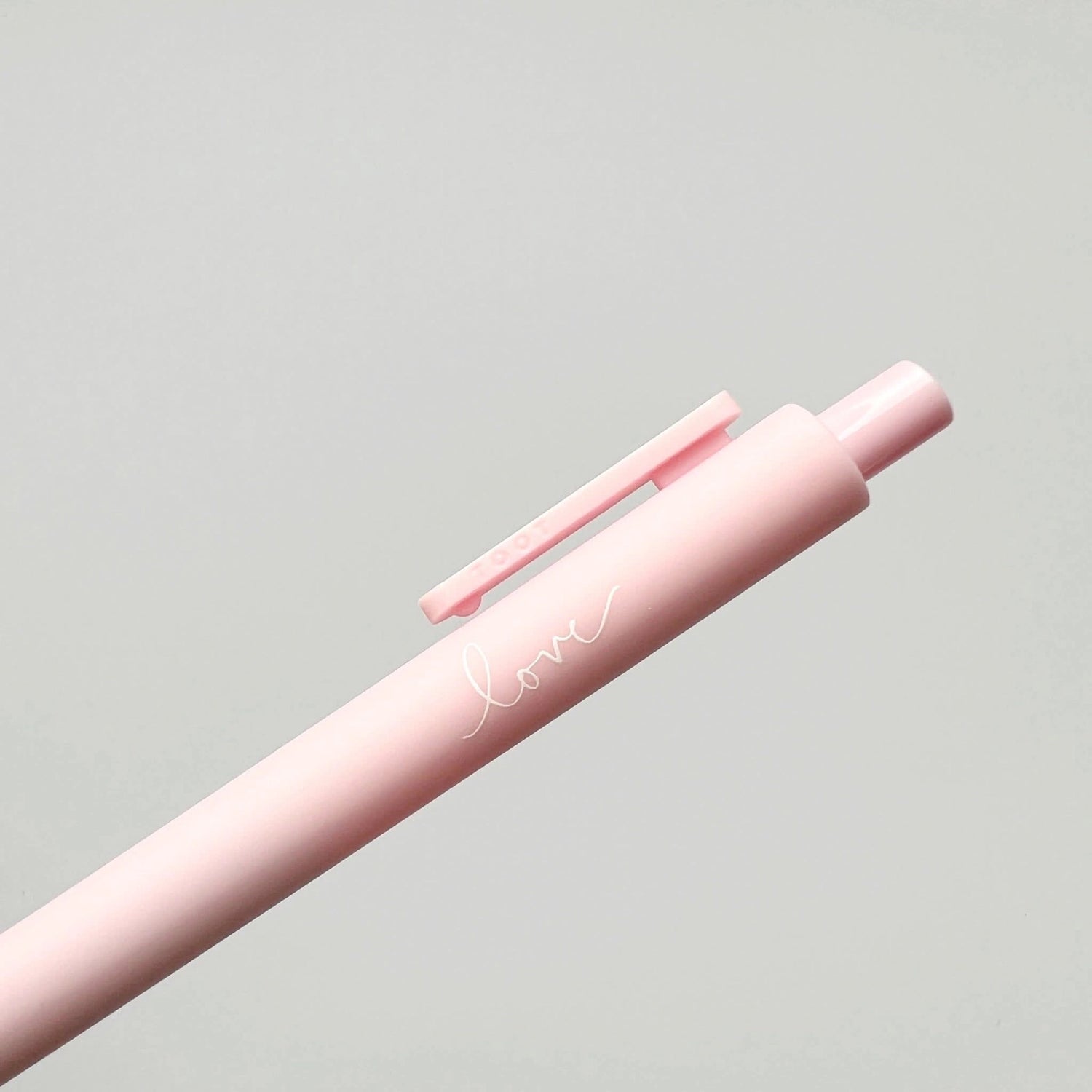 Pink pen with 'love' engraving on a light gray background