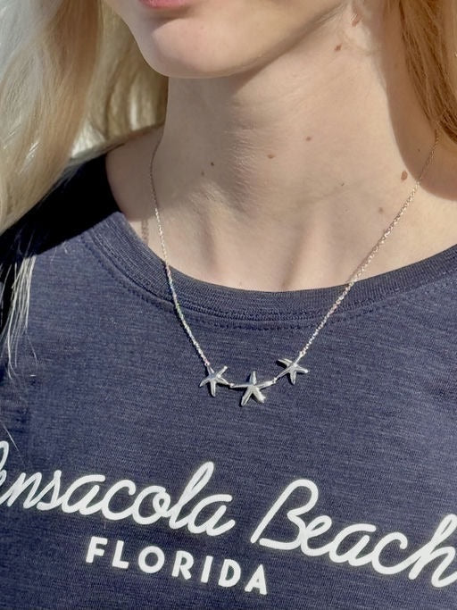sterling silver starfish trio necklace worn with a crewneck top, showing length and placement.