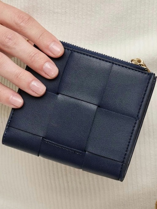 Navy blue quilted wallet held by a hand on a beige background
