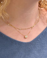 Close-up of a person wearing a gold necklaces with a blue top