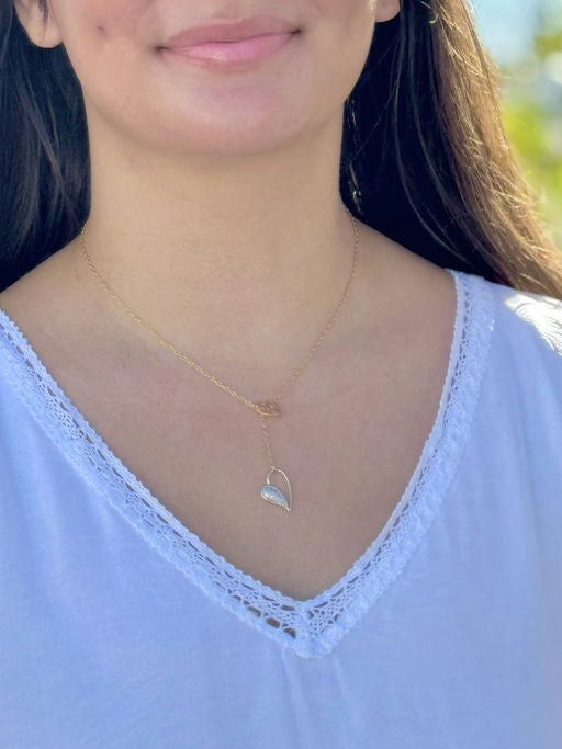 Model wearing a gold plated sterling silver lariat necklace with pavé drop pendant, styled with a white lace-trim top