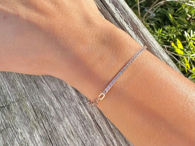 Model wearing a rose gold plated sterling silver bracelet with pavé bar detail, photographed outdoors on a wrist