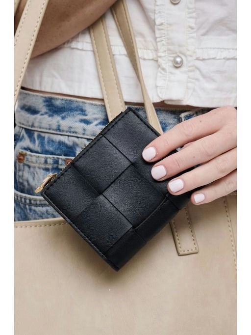 Black woven wallet held by a person wearing a white shirt and blue jeans.