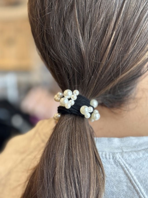 Hair tie with pearls in a ponytail against a blurred background