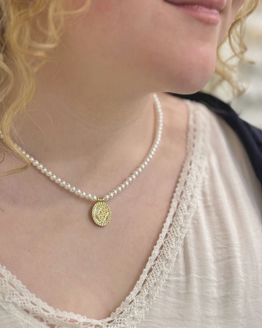 Pearl necklace with a gold pendant worn by a person