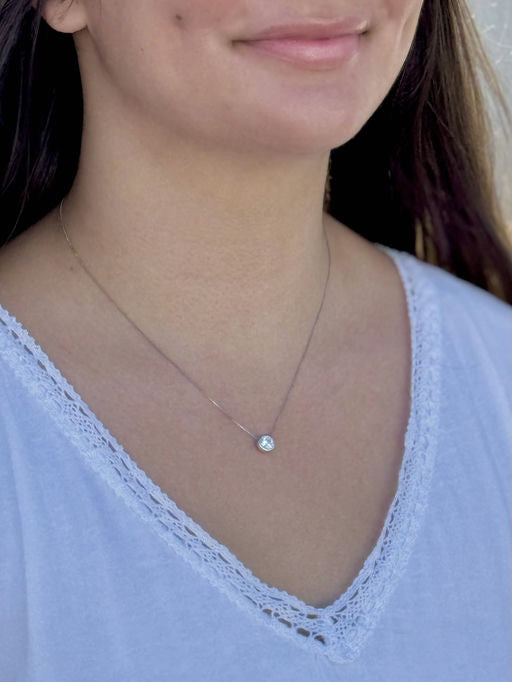 Close-up of a person wearing a delicate necklace with a small pendant.