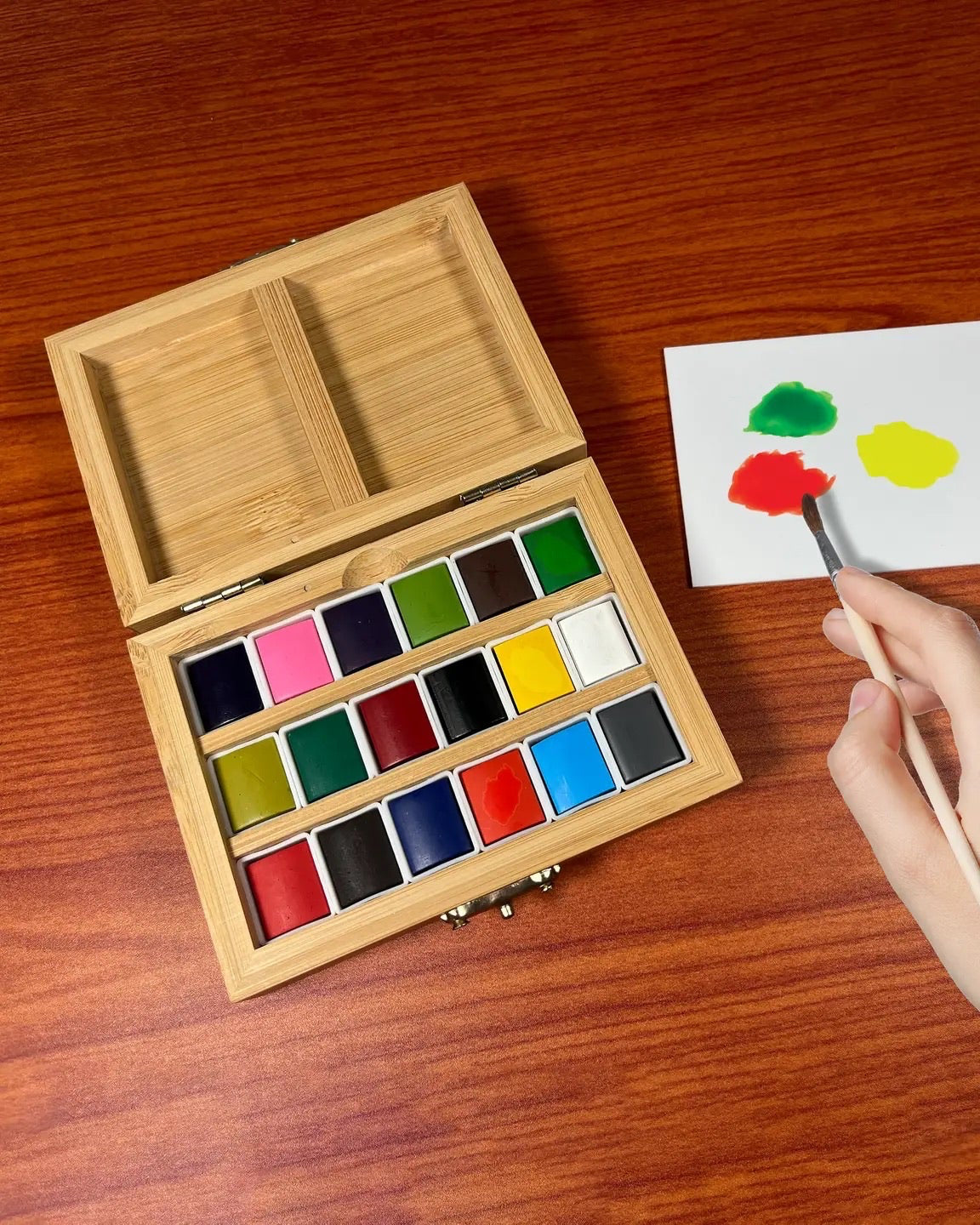 Wooden watercolor set with paint swatches on a wooden surface