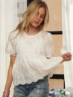 Woman wearing a white lace blouse and blue jeans.