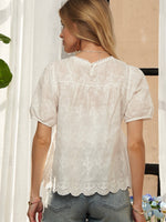 Woman wearing a white lace blouse and blue jeans.