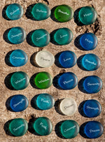 Set of sea glass pebbles with motivational phrases on a textured surface