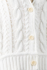 Close-up of a white knitted cardigan with button details