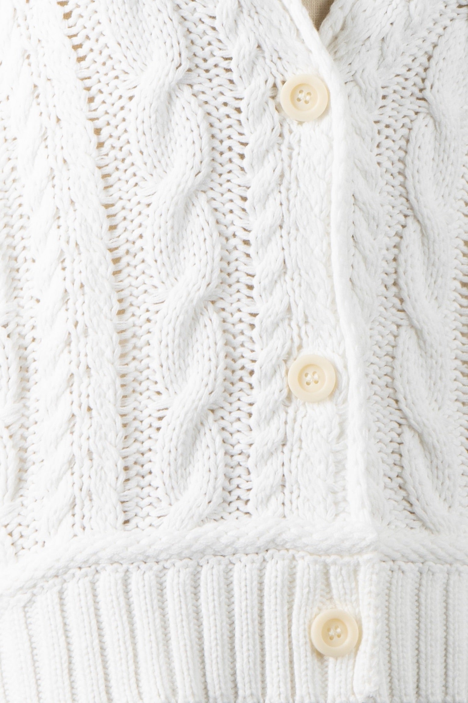 Close-up of a white knitted cardigan with button details