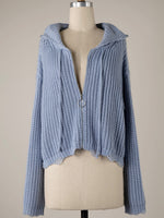 Blue knitted cardigan on a mannequin against a beige background