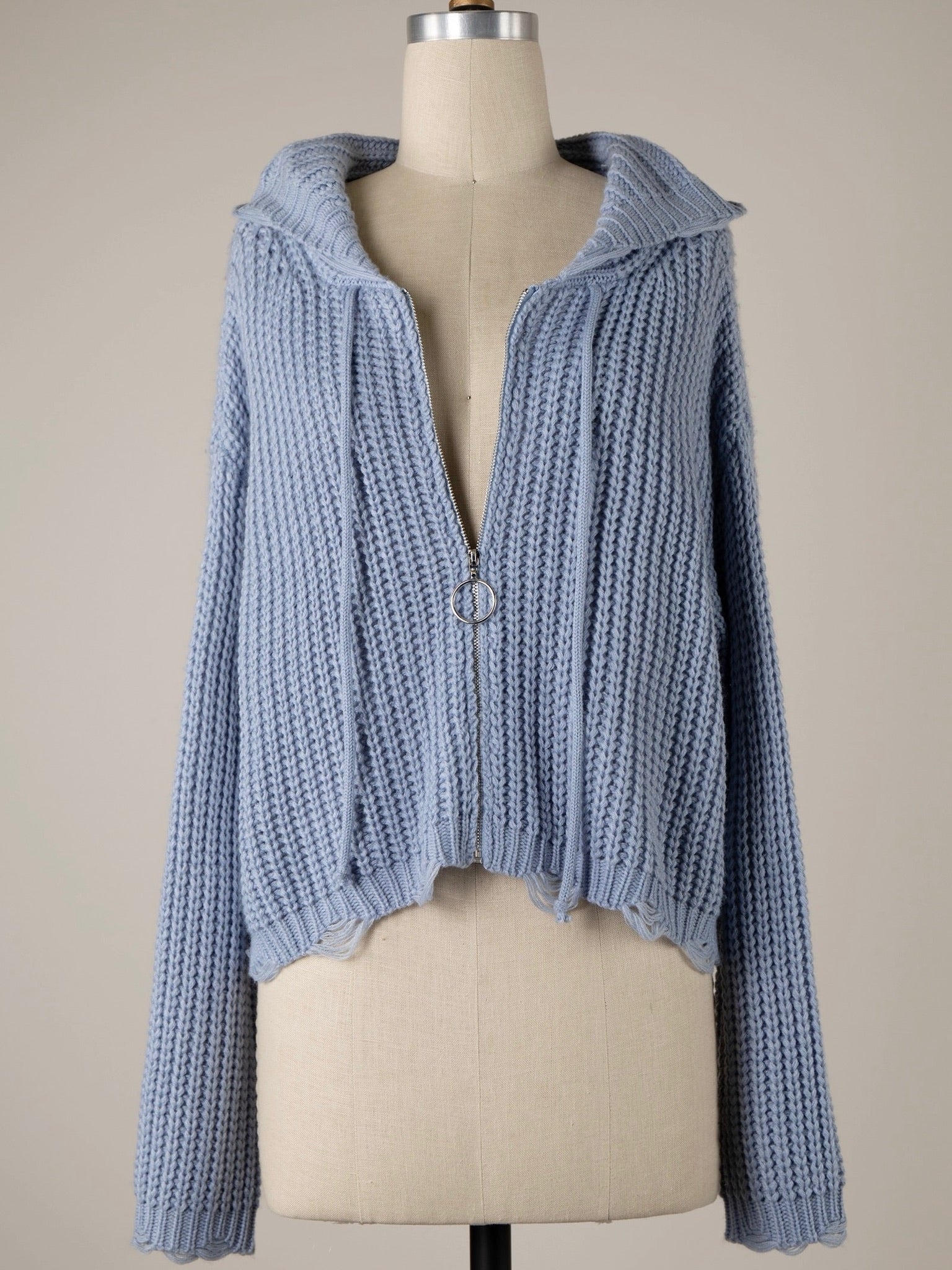 Blue knitted cardigan on a mannequin against a beige background