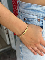Gold bracelet on a wrist with a blurred background