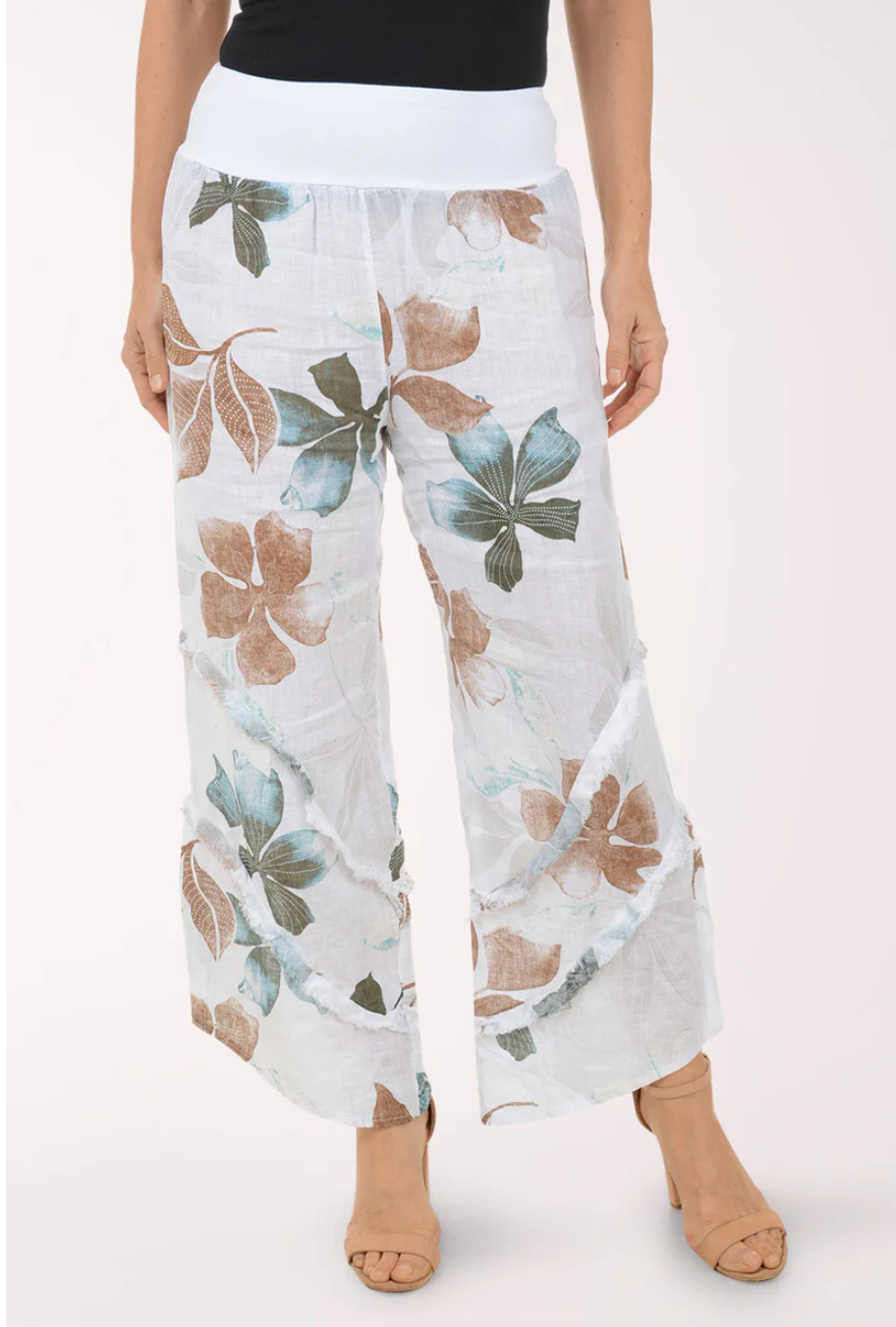 Linen Pants in White Floral featuring a relaxed wide-leg silhouette, soft pull-on waistband, and oversized botanical print in muted sage green, aqua, and sand tones on lightweight white linen fabric.
