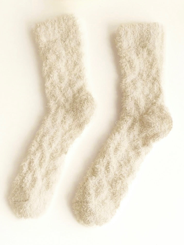 Pair of beige fuzzy socks on a white background