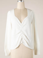 White sweater on a mannequin against a plain background