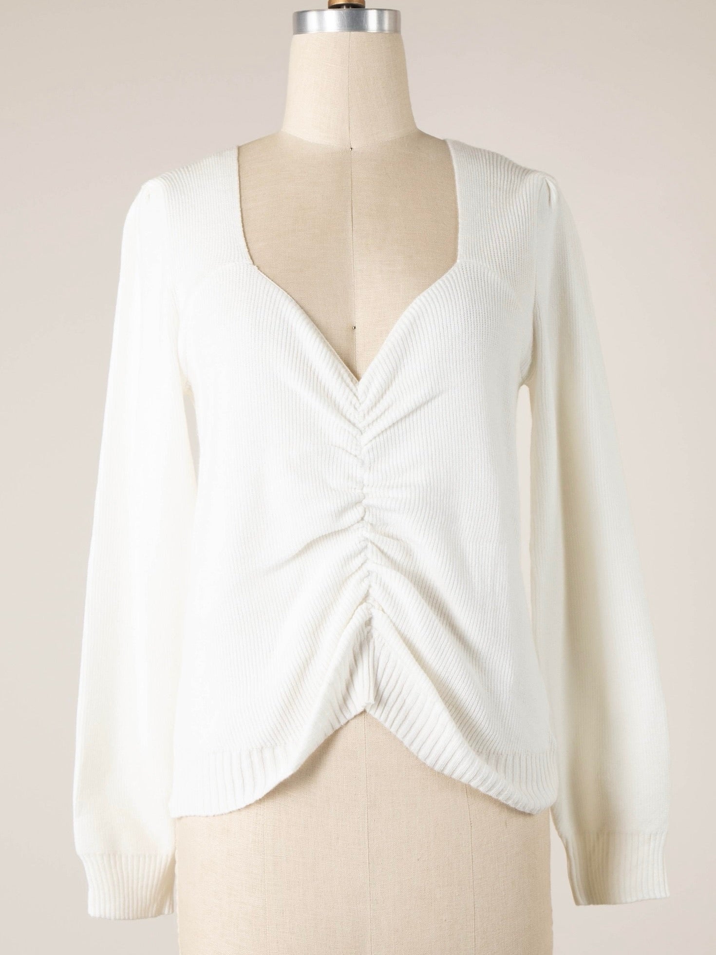 White sweater on a mannequin against a plain background