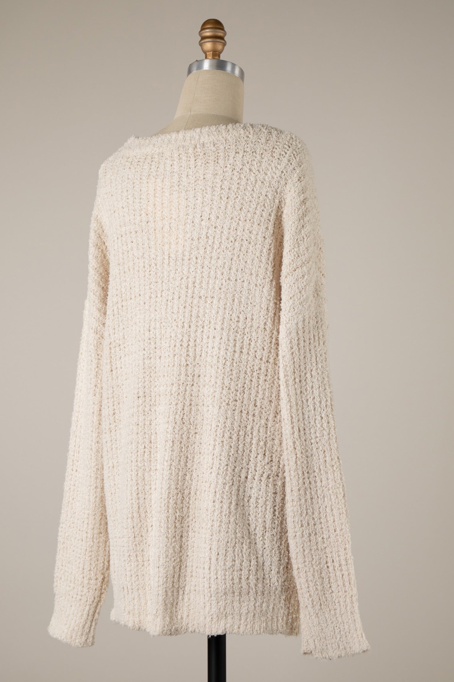 Beige textured sweater on a mannequin against a plain background