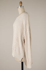 Beige knitted sweater on a mannequin against a plain background