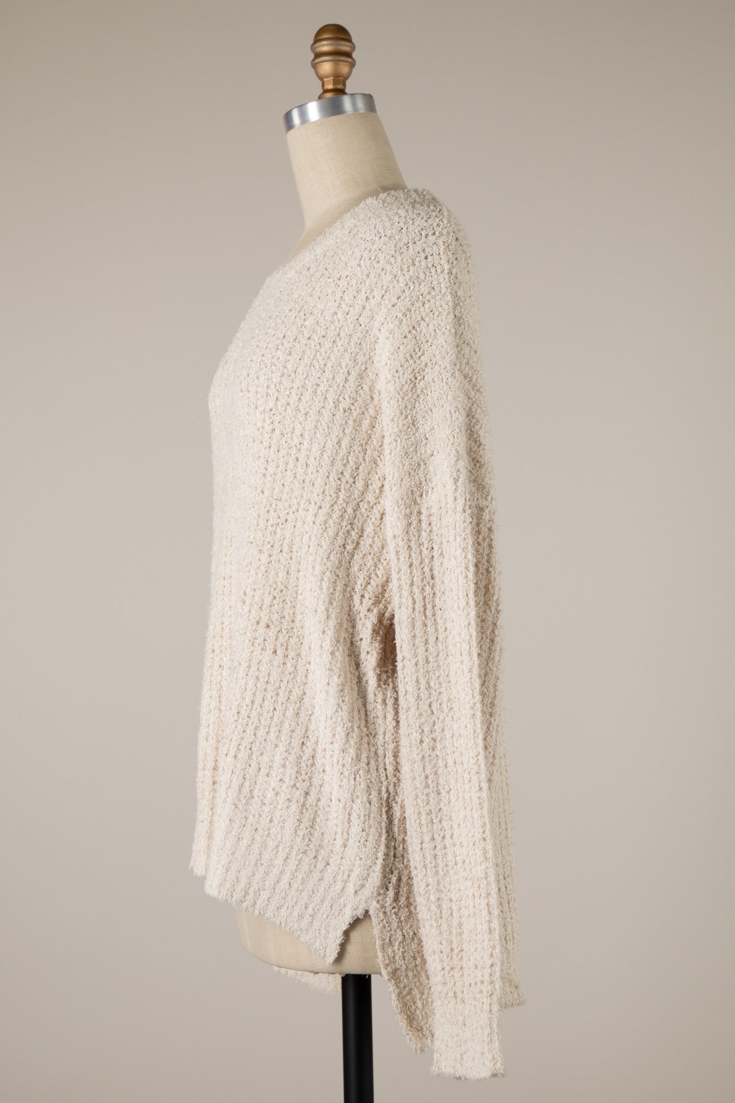 Beige knitted sweater on a mannequin against a plain background