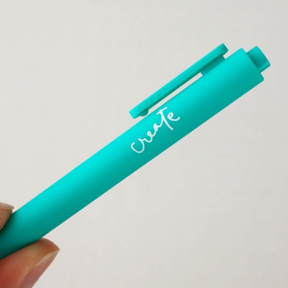 Teal pen with 'create' written on it against a light gray background