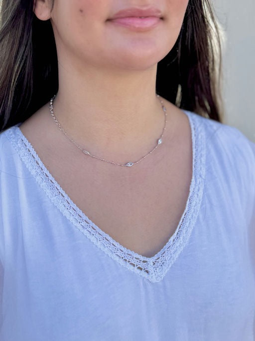 Model wearing a delicate sterling silver necklace with marquise-shaped stations, styled with a white lace-trim top