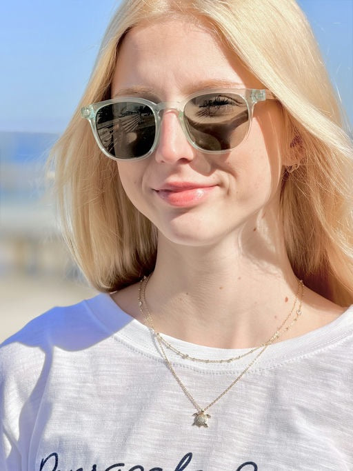 Woman wearing sunglasses with a blurred beach background