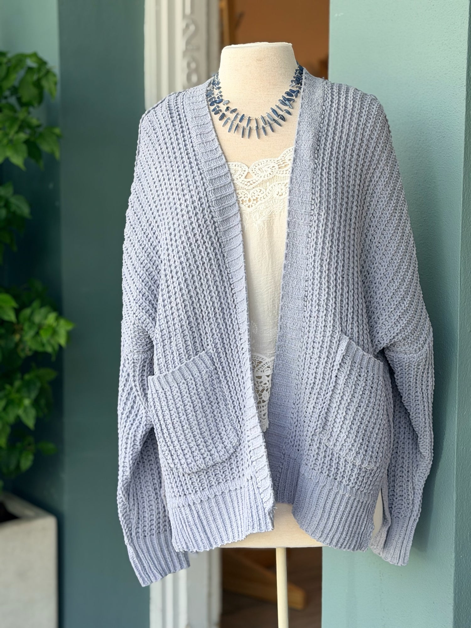 Front view of the Isabelle Sweater Cardigan in blue grey, styled over a lace-trim top on a mannequin at Ardor Boutique.