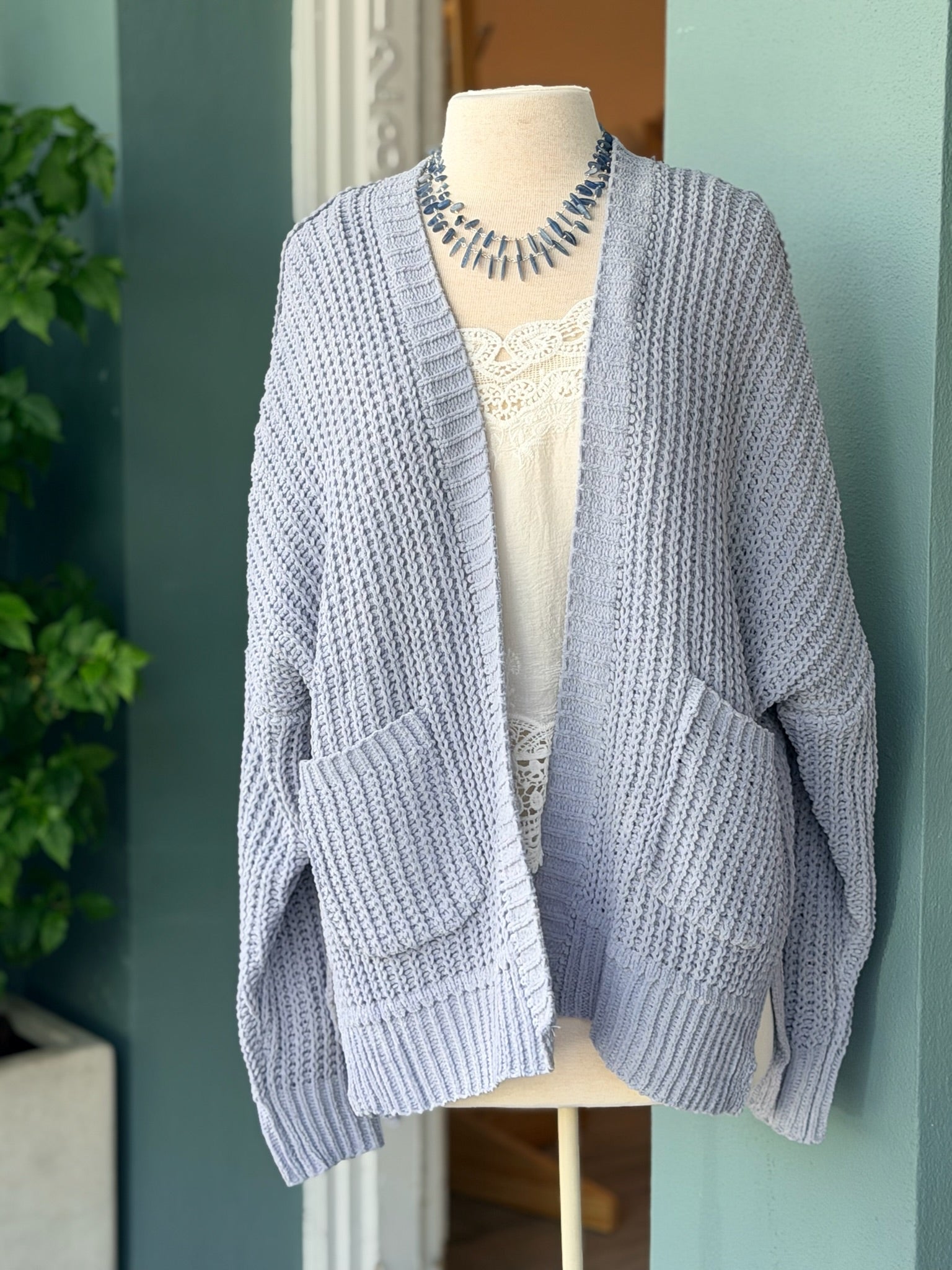Front view of the Isabelle Sweater Cardigan in blue grey, styled over a lace-trim top on a mannequin at Ardor Boutique.