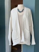 Front view of the Isabelle Sweater Cardigan in ivory cream, styled over a sequin top on a mannequin at Ardor Boutique.