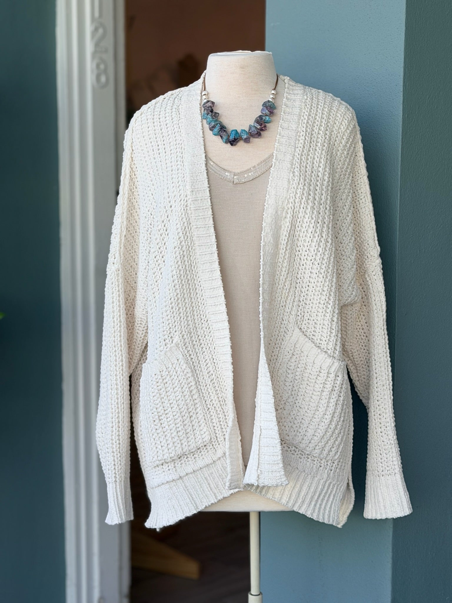 Front view of the Isabelle Sweater Cardigan in ivory cream, styled over a sequin top on a mannequin at Ardor Boutique.