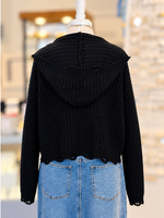 Kennedy Hoodie in black featuring textured open knit, a full zipper with ring pull, hood, and cropped distressed hem, styled with denim at Ardor Boutique.