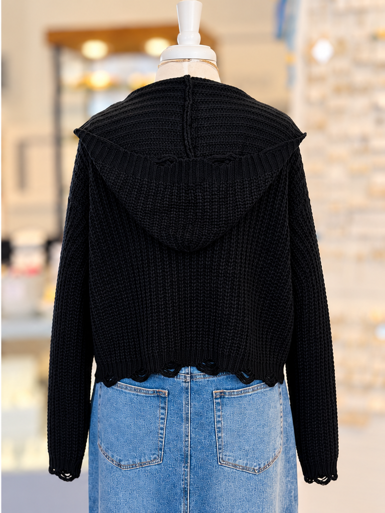 Kennedy Hoodie in black featuring textured open knit, a full zipper with ring pull, hood, and cropped distressed hem, styled with denim at Ardor Boutique.