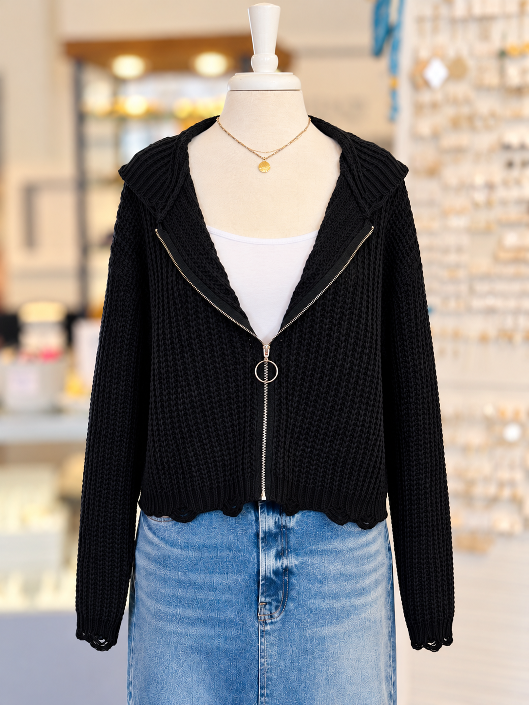 Kennedy Hoodie in black featuring textured open knit, a full zipper with ring pull, hood, and cropped distressed hem, styled with denim at Ardor Boutique.