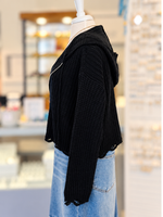 Kennedy Hoodie in black featuring textured open knit, a full zipper with ring pull, hood, and cropped distressed hem, styled with denim at Ardor Boutique.