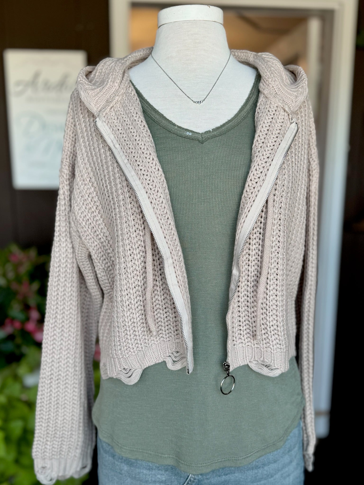 Front view of the Kennedy Hoodie in sandy beige featuring a soft cotton-blend knit, silver zip front, drawstring hood, cropped fit, and distressed hem at Ardor Boutique.