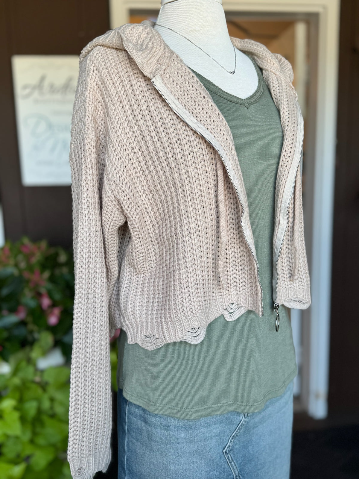 Side view of the beige Kennedy Hoodie showing its relaxed cropped silhouette, textured knit, long sleeves, hood, and distressed hem detailing at Ardor Boutique.
