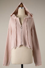 Pink knitted hoodie on a mannequin against a neutral background