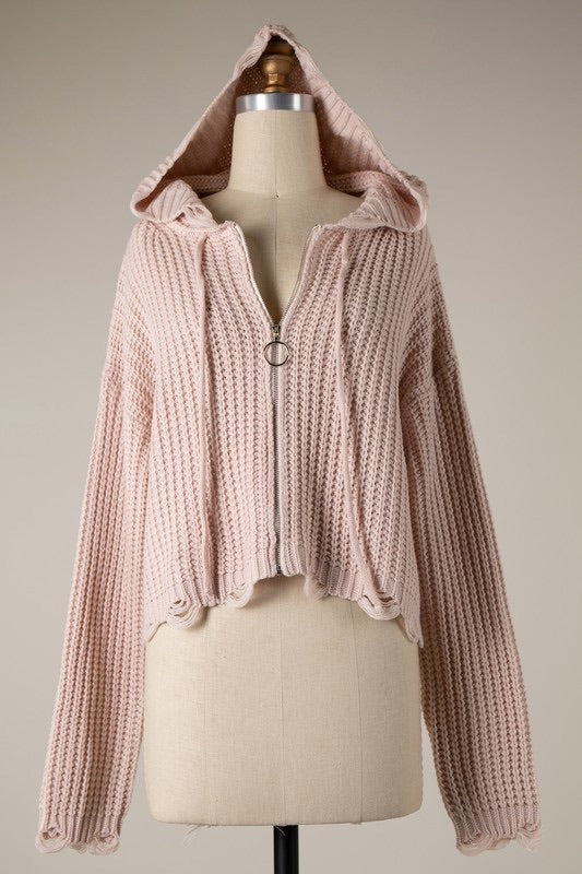 Pink knitted hoodie on a mannequin against a neutral background