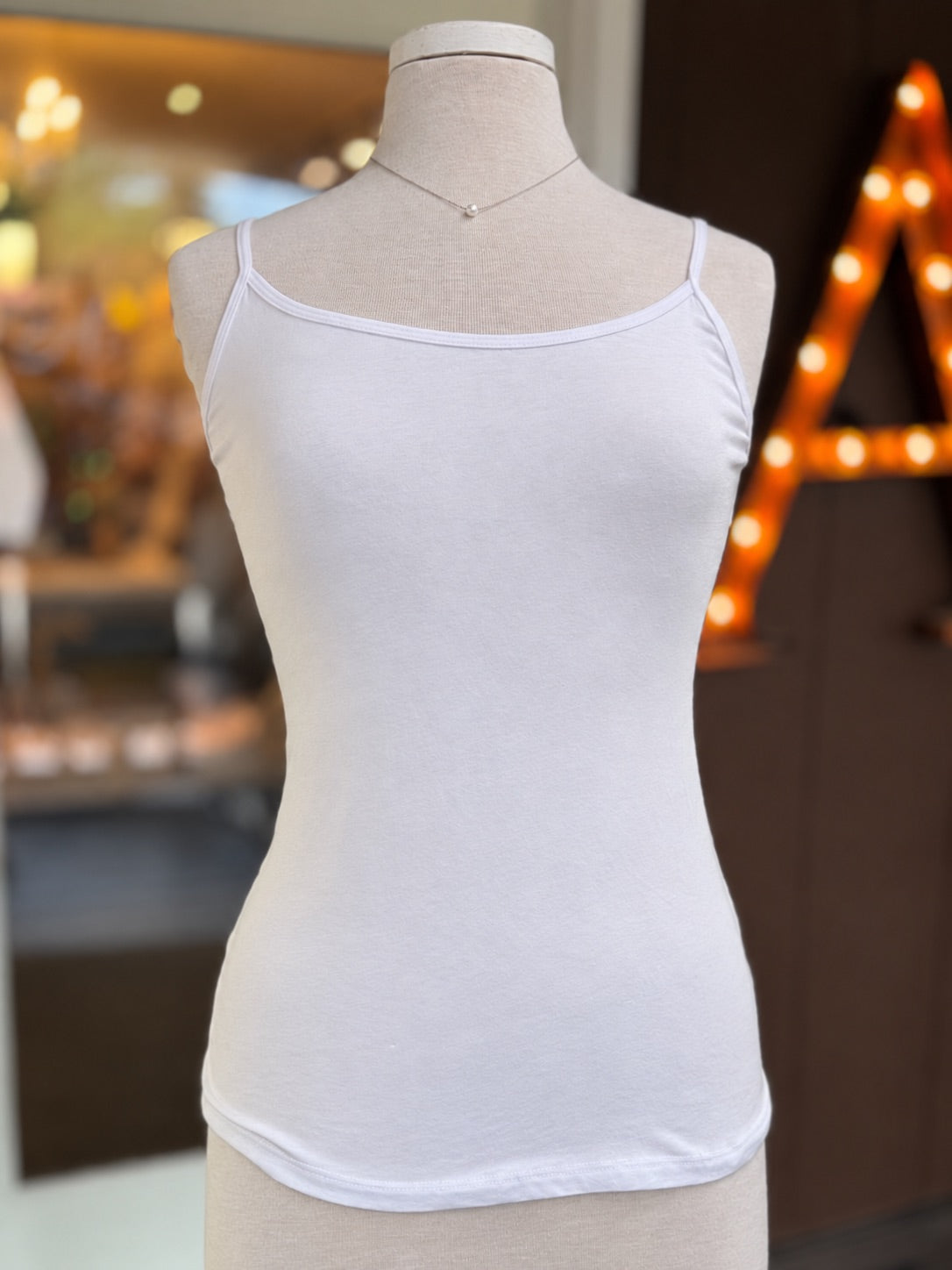 White Lena Basic Tank displayed on a mannequin with adjustable spaghetti straps, scoop neckline, and simple fitted silhouette at Ardor Boutique.